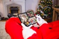 Santa claus making laptop christmas group video call with four diverse smiling families