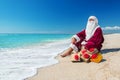 Santa Claus with many golden gifts relaxing at beach