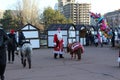 Santa Claus on New Year`s Day offers to pounce on children. It is located on the square, on which there are many people and shops.