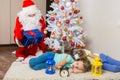 Santa Claus in New Years Eve gifts lays out and looked at the fallen asleep in front of Christmas tree two children Royalty Free Stock Photo