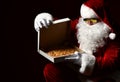 Santa Claus in sunglasses is opening closing pizza box, looking inside, desiring on black. New year and Xmas fast food