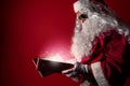 Santa Claus opening a gift box full of Christmas magic dust on a red background Royalty Free Stock Photo