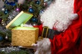 Santa Claus opening magic glowing gift box with Christmas tree on back side Royalty Free Stock Photo