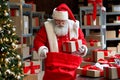 Santa Claus packing present gift boxes in sack bag preparing fast xmas delivery.
