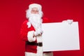 Santa Claus pointing in blank advertisement banner isolated on red background with copy space Royalty Free Stock Photo