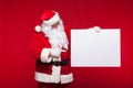 Santa Claus pointing in blank advertisement banner isolated on red background with copy space Royalty Free Stock Photo