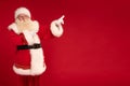 Santa Claus pointing on empty red studio background. Merry Christmas and Happy New Year! A lot of copy space. Xmas sale, discount Royalty Free Stock Photo