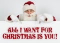 Santa Claus points his fingers at the board with the text - ALL I WANT FOR CHRISTMAS IS YOU Royalty Free Stock Photo
