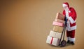 Santa Claus with presents stacked on a delivery trolley in a postal theme with a plain background and copy space