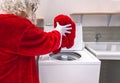 Santa Claus putting his clothes in the washing machine