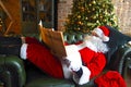 Santa claus reading business newspaper while sitting on sofa Royalty Free Stock Photo