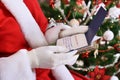 Santa claus reading letters from children in front of christmas