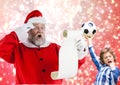 Santa claus reading wish list and excited boy with football Royalty Free Stock Photo