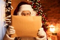 Santa Claus reading wish list in festively decorated room Royalty Free Stock Photo