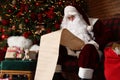 Santa Claus reading wish list near Christmas tree Royalty Free Stock Photo