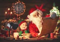santa claus reads list of good children to little elf by Christmas tree