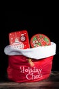 Santa Claus red bag with presents and gift showing Holiday Cheer. Isolated on black background