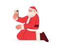 santa claus in red costume kneeling on floor and using cell phone happy new year merry christmas holidays celebration Royalty Free Stock Photo