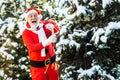 Santa Claus in red costume walk in winter forest. Wish you merry Christmas. Father Christmas brings gifts to children. Royalty Free Stock Photo