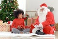 Santa Claus in red dress costume and curly hair African cute girl holding red ornament balls for decorating beautiful Christmas Royalty Free Stock Photo