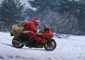 Santa Claus on red motorcycle with a sack driving along winter s Royalty Free Stock Photo