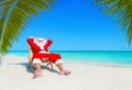 Santa Claus relax in sunlounger at sandy tropical palm beach Royalty Free Stock Photo
