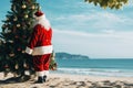 Santa Claus at sea beach with decorated christmas tree happy new year concept Royalty Free Stock Photo