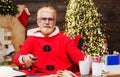 Santa Claus sitting in armchair watching Christmas movie holding remote control. New Year cinema at home. Royalty Free Stock Photo