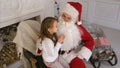 Santa Claus sitting in a chair with a little girl dreaming about her Christmas presents Royalty Free Stock Photo