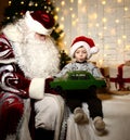 Santa Claus sitting with happy little cute baby boy kid near Christmas tree Royalty Free Stock Photo