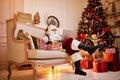 Santa Claus sitting at his home and reading email on laptop with ÃÂhristmas requesting or wish list near the fireplace and tree Royalty Free Stock Photo