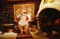 Santa Claus is sitting in his office by the fireplace