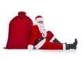 Santa Claus sitting near huge red Christmas sack full of gifts and surprises isolated on white background, New Year`s Day holiday Royalty Free Stock Photo