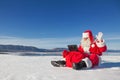 Santa Claus sitting on snow, looking at laptop news Royalty Free Stock Photo