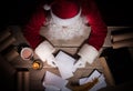 Santa Claus sitting at the table in his room and opening Christmas letter from child Royalty Free Stock Photo