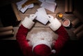 Santa Claus sitting at the table in his room and opening Christmas letter from child Royalty Free Stock Photo