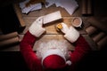 Santa Claus sitting at the table in his room and reading Christmas letter from child Royalty Free Stock Photo