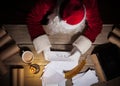 Santa Claus sitting at the table in his room and reading Christmas letter from child Royalty Free Stock Photo