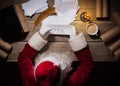 Santa Claus sitting at the table in his room and reading Christmas letter from child Royalty Free Stock Photo