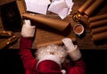 Santa Claus sitting at the table in his room and reading Christmas letter or wish list Royalty Free Stock Photo