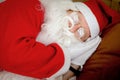 Santa Claus sleeping comfortably, elderly senior old man with white long beard in Santa Claus costume taking a nap after working Royalty Free Stock Photo
