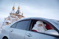 Santa Claus and Snow Maiden in the car against the background of the winter church.