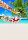 Christmas Santa Claus relax in hammock under palm tree at tropical sandy ocean beach Royalty Free Stock Photo