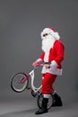 Santa Claus in sunglasses and headphones puts the bike on the back wheel on the white background. Royalty Free Stock Photo