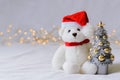 Santa claus teddy bear eyes who wearing hat sitting with blurred focus Christmas tree Royalty Free Stock Photo