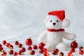 Santa claus teddy bear eyes who wearing hat sitting with red Christmas baubles Royalty Free Stock Photo