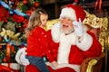 Santa Claus tells a funny story to a cute little girl on the holiday of Christmas.