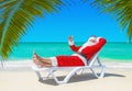 Santa Claus thumbs up gesturing on sunlounger at tropical palm b Royalty Free Stock Photo