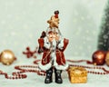 Santa Claus toy brings Christmas tree at blue snowy night bokeh background and blurred lights foreground. Royalty Free Stock Photo