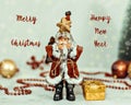 Santa Claus toy brings Christmas tree at blue snowy night bokeh background and blurred lights foreground. Royalty Free Stock Photo